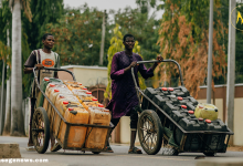 A rural African woman fetching clean water from a public tap in her village.