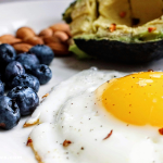 Healthy morning foods including eggs, berries, oats, and avocado toast on a breakfast table.