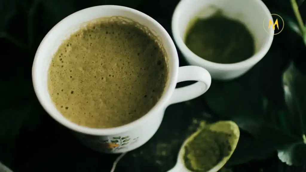 A cup of vibrant green matcha tea with bamboo whisk
