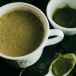 A cup of vibrant green matcha tea with bamboo whisk