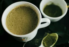 A cup of vibrant green matcha tea with bamboo whisk